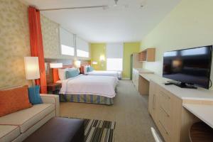 ポートランドにあるHome2 Suites by Hilton Portlandのベッド1台、薄型テレビが備わるホテルルームです。