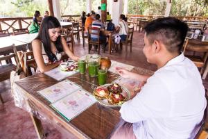 un hombre y una mujer sentados en una mesa con un plato de comida en Cabañas Santa Cruz Homún, en Homún