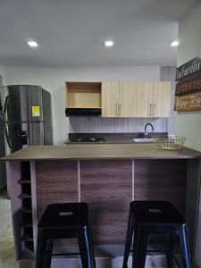 een keuken met een aanrecht met twee zwarte krukken bij Apartamentos del Sur in Itagüí