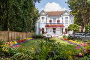 a white house with flowers in the yard at Balincourt in Bournemouth