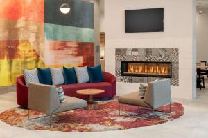 a living room with a couch and two chairs and a fireplace at Homewood Suites By Hilton Belmont in Belmont