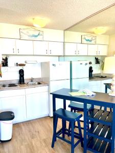una cocina con una mesa azul y algunos armarios blancos en Waters Edge - Ocean View at Symphony Beach Club en Ormond Beach