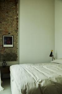 een slaapkamer met een wit bed en een bakstenen muur bij Stadtflucht Loft 5.2.2 in Berlijn
