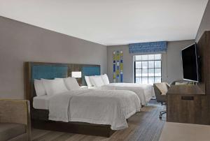 a hotel room with two beds and a flat screen tv at Hampton Inn Westfield in Westfield