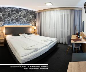 a hotel room with a large bed and a desk at Hotel Kamzík *** in Malá Morávka