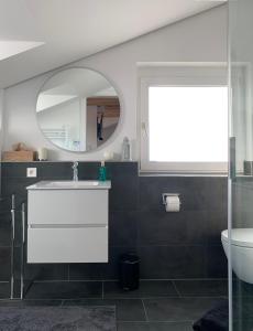 La salle de bains est pourvue d'un lavabo blanc et d'un miroir. dans l'établissement Klimatisierte Loftwohnung, à Leura
