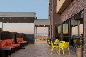 a patio with yellow chairs and tables on a building at Home2 Suites By Hilton Carlsbad New Mexico in Carlsbad