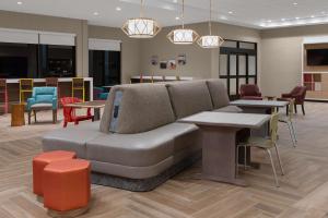 a living room with a couch and tables and chairs at Home2 Suites By Hilton Carlsbad New Mexico in Carlsbad