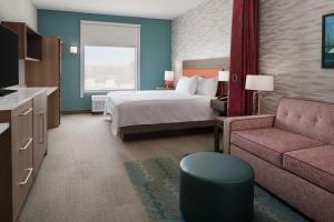 a hotel room with a bed and a couch at Home2 Suites By Hilton Carlsbad New Mexico in Carlsbad
