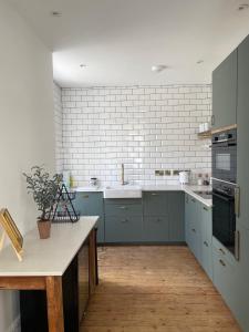 a kitchen with blue cabinets and a white brick wall at The Old Tearoom At Ty Llywelyn By Birch Stays in Conwy