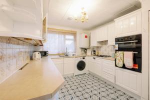 kuchnia z białymi szafkami i blatem w obiekcie Home near Excel, Stratford and Canary Wharf w Londynie