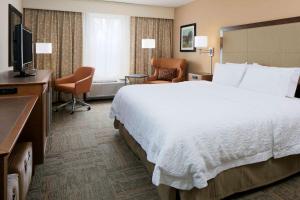 a hotel room with a large bed and a television at Hampton Inn Kansas City/Shawnee Mission in Shawnee
