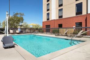 a swimming pool with chairs and a building at Hampton Inn Pell City in Pell City