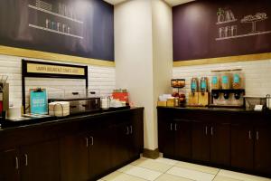 a kitchen with brown cabinets and a counter with drinks at Hampton Inn Doylestown in Warrington