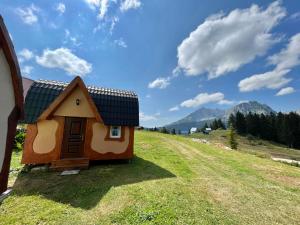 a tiny house on a hill with mountains in the background at Bungalows Fairy tale in Žabljak