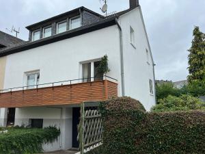 Casa blanca con balcón de madera. en Gästehaus Melitta, en Stadtkyll