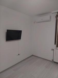 Dieses weiße Zimmer verfügt über einen Flachbild-TV an der Wand. in der Unterkunft Restoran BMB in Odžak