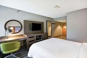 um quarto de hotel com uma cama, uma secretária e uma televisão em Hampton Inn Seattle/Southcenter em Tukwila