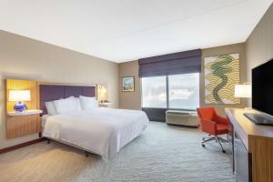 een hotelkamer met een bed, een bureau en een televisie bij Hampton Inn & Suites Albany-Airport in Latham