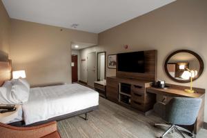 Habitación de hotel con cama, escritorio y TV. en Hampton Inn Springfield, en Springfield