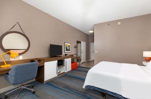 a hotel room with a bed and a desk and a mirror at Hampton Inn Corbin in Corbin