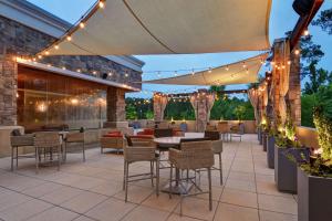 un patio con mesas, sillas y luces en Embassy Suites by Hilton Raleigh Durham Airport Brier Creek, en Raleigh