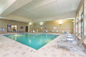 uma piscina num quarto de hotel com cadeiras e mesas em Doubletree by Hilton Pleasant Prairie Kenosha, WI em Pleasant Prairie