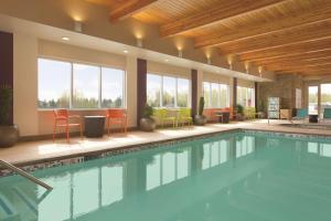 a swimming pool in a hotel with chairs and tables at Home2 Suites by Hilton Bellingham in Bellingham