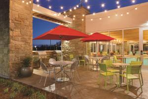 patio ze stołami, krzesłami i czerwonymi parasolami w obiekcie Home2 Suites by Hilton Bellingham w mieście Bellingham