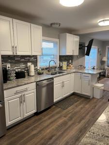 uma cozinha com armários brancos e electrodomésticos de aço inoxidável em Charming and Happy Walled Lake MI Cottage em Novi