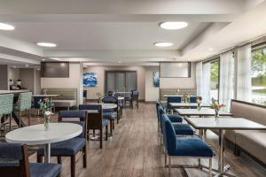a dining room with tables and blue chairs at Hampton Inn Chicago-O'Hare International Airport in Schiller Park
