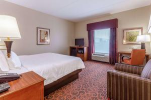 a hotel room with a bed and a chair at Hampton Inn Owings Mills in Owings Mills