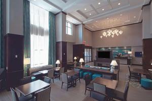 Hampton Inn & Suites Columbus/University Area في كولومبوس: لوبي الفندق به طاولات وكراسي وتلفزيون