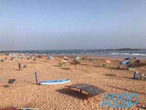 a beach with people and umbrellas and the ocean at chez mehdi in Skhirat