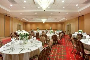 una sala de banquetes con mesas y sillas blancas en Hilton Stockton, en Stockton