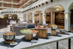 a buffet in a hotel lobby with bowls of food at Embassy Suites by Hilton Tulsa I-44 in Tulsa