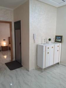 Cette chambre est dotée d'un mur blanc, d'une armoire et d'un téléphone. dans l'établissement Appartement Dar Meknès, à Meknès