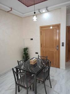 Appartement Dar Meknès في مكناس: طاولة طعام مع أربعة كراسي وباب خشبي
