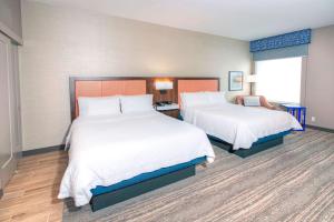 a hotel room with two beds and a chair at Hampton by Hilton Ottawa in Ottawa