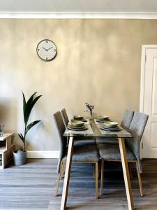 a dining room table with chairs and a clock on the wall at Cosy bright home in Murrayfield in Edinburgh