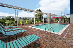 una piscina con 2 bancos, mesa y sillas en Home2 Suites by Hilton Harvey New Orleans Westbank, en Harvey