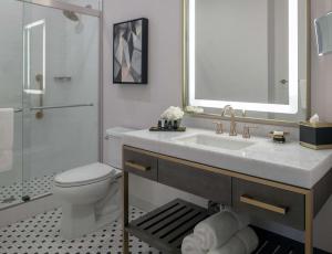 a bathroom with a sink and a toilet and a mirror at Tulsa Club Hotel Curio Collection By Hilton in Tulsa