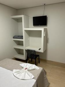 a bedroom with a bed and a tv on a wall at Bravo City Hotel Urupês 