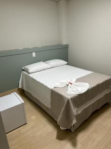 a bedroom with a large bed with a white sheet at Urupês Hotel in Urupês