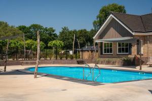 a swimming pool in front of a house at Lodge Damian op de Veluwe in Voorthuizen