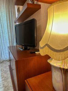 einen Fernseher auf einem Holzschrank mit Lampe in der Unterkunft Apartment Alex in Athen
