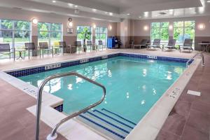 a pool in a hotel with tables and chairs at Hampton Inn Cranbury in Cranbury