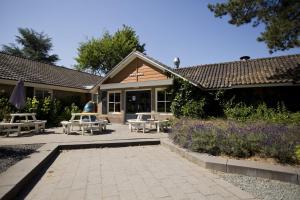 a patio with tables and benches in front of a building at Lodge Damian op de Veluwe in Voorthuizen