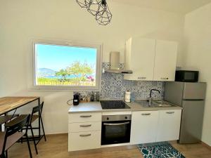 uma cozinha com armários brancos, uma mesa e uma janela em Villa Tany em Capoliveri