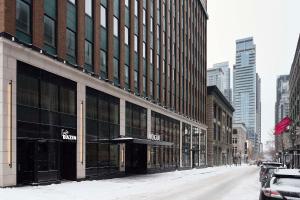 a snow covered city street with a large building at Vogue Hotel Montreal Downtown, Curio Collection by Hilton in Montreal